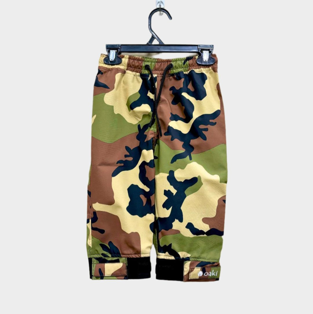 A pair of kids rain pants with an elastic waistband and drawstring. Ankles have a neoprene covered velcro adjustment. Shown in a classic camo pattern of green, brown, tan, and black
