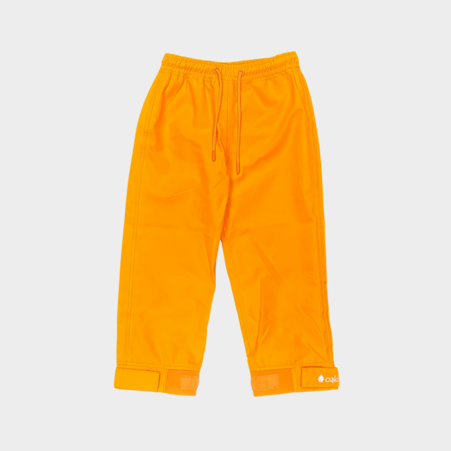 A pair of kids rain pants with an elastic waistband and drawstring. Ankles have a neoprene covered velcro adjustment. Shown in lava orange