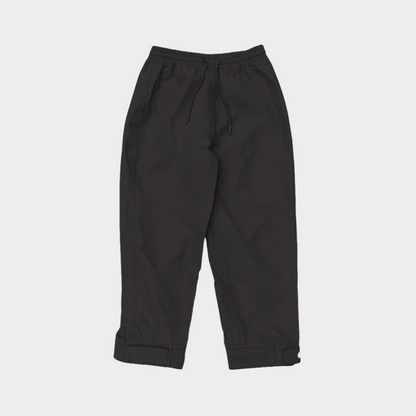 A pair of kids rain pants with an elastic waistband and drawstring. Ankles have a neoprene covered velcro adjustment. Shown in black