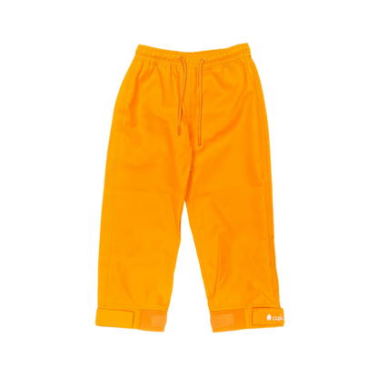 A pair of kids rain pants with an elastic waistband and drawstring. Ankles have a neoprene covered velcro adjustment. Shown in lava orange