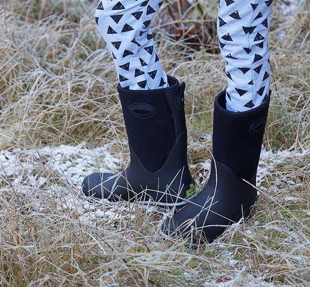 Black rubber boots worn with patterned leggings on a frosty grass background